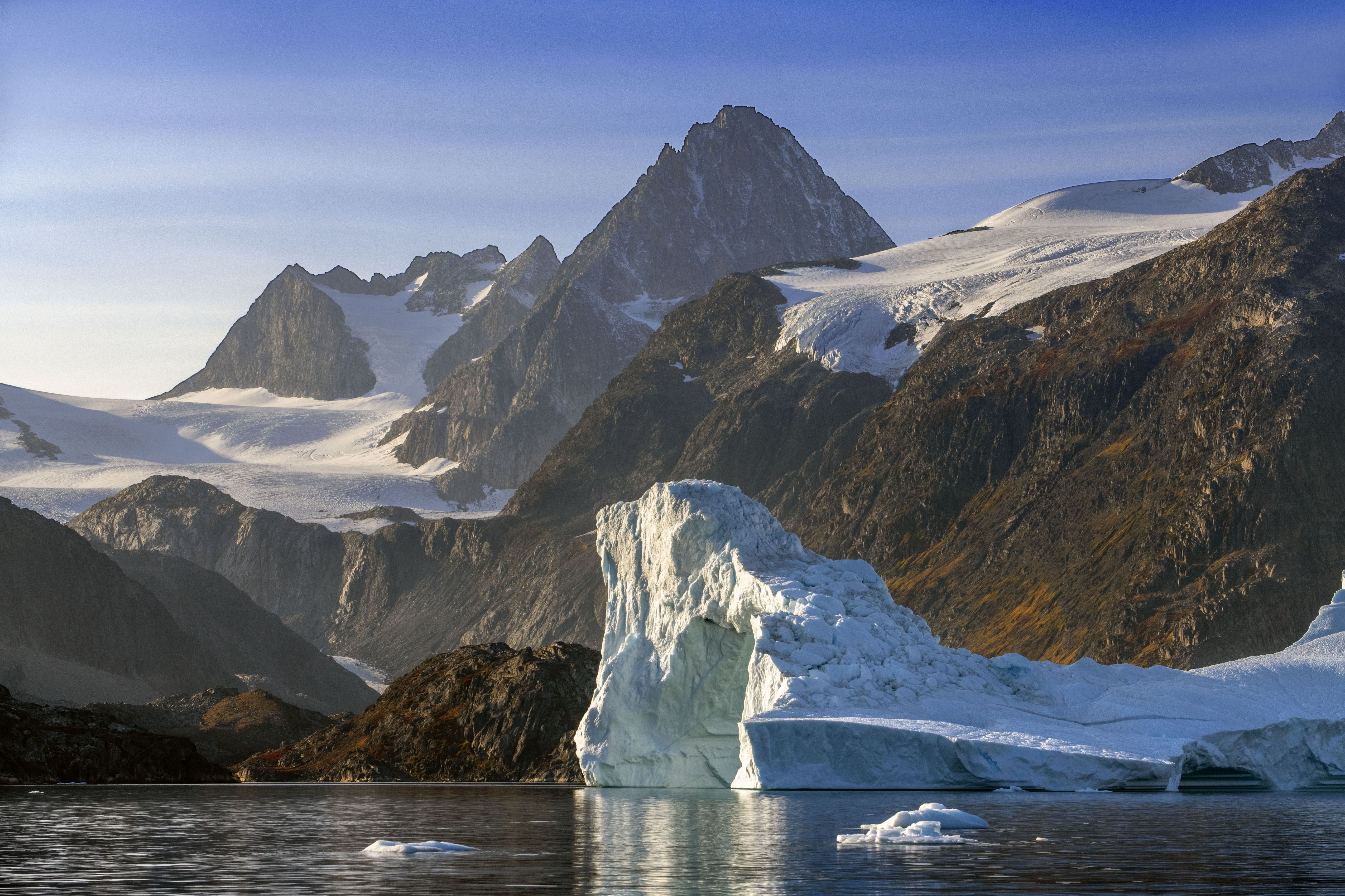 Skjoldungen Fjord, a large iceberg  surrounded by snow-capped mountains, Southeast coast, Greenland. 