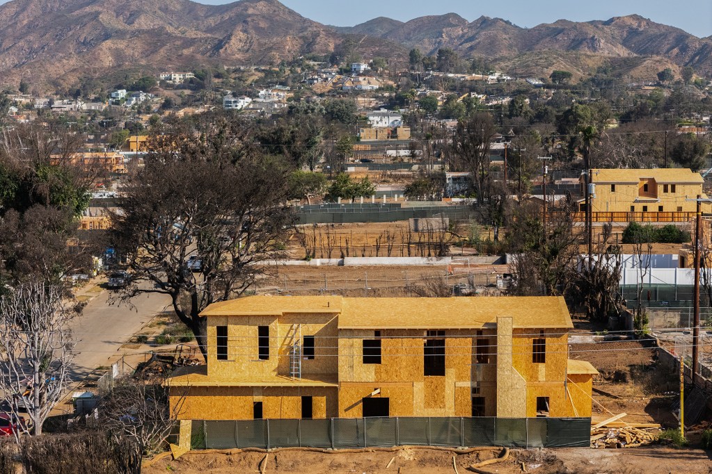 An aerial view of the framing of a two-story home under construction in a neighborhood that was burned down by a wildfire.