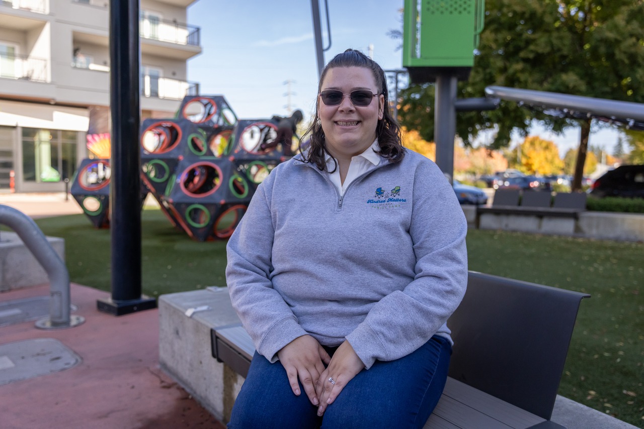 A photo of a woman sitting on a bench near a playground
