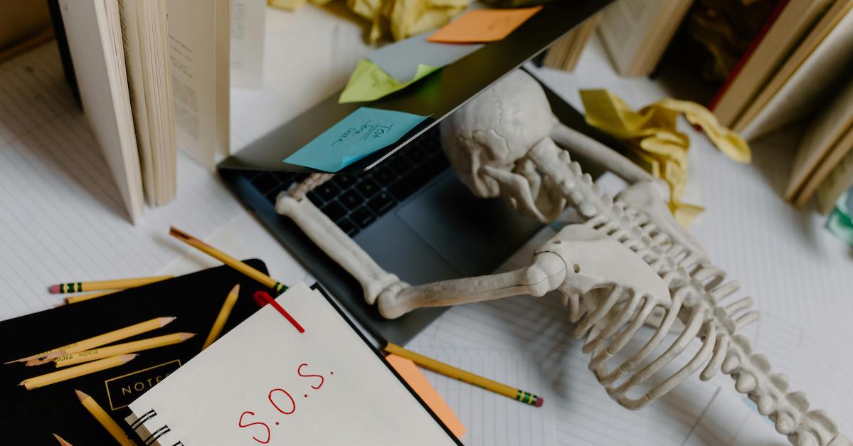 A skeleton collapsed under a laptop. 