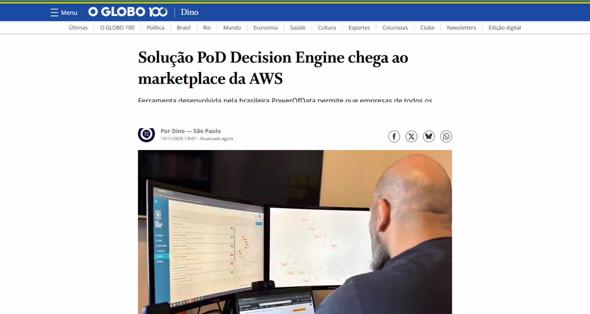 Man with a bald head and beard working on a computer with three monitors displaying data and maps.