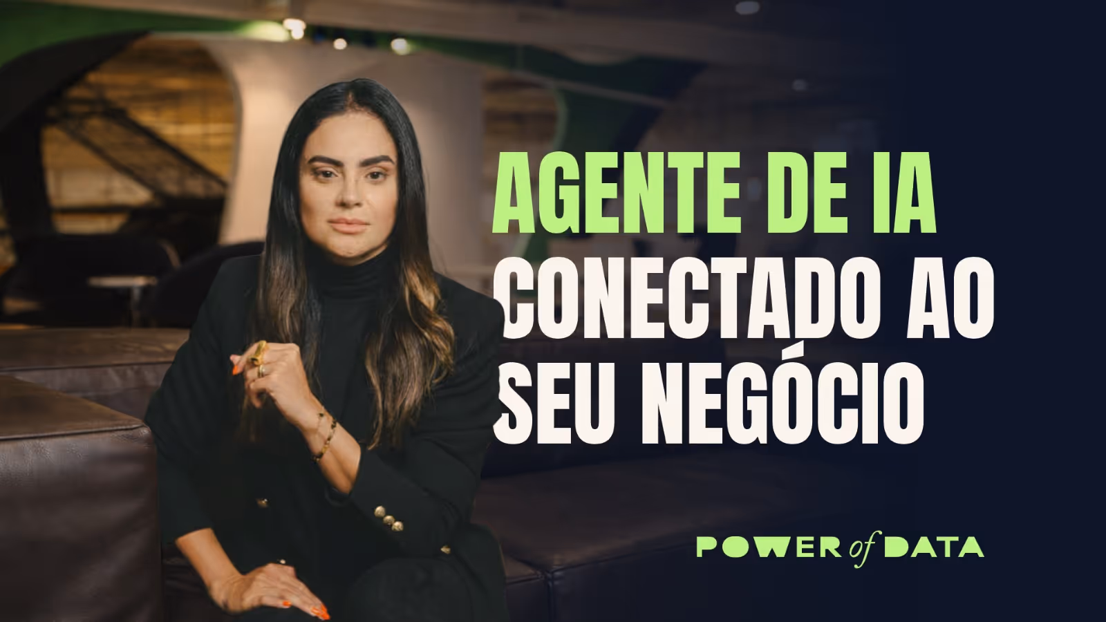 Mulher de cabelos longos e escuros, vestindo terno preto, sentada em sofá marrom em ambiente interno, com texto verde e branco ao lado sobre agente de IA conectado a negócios.