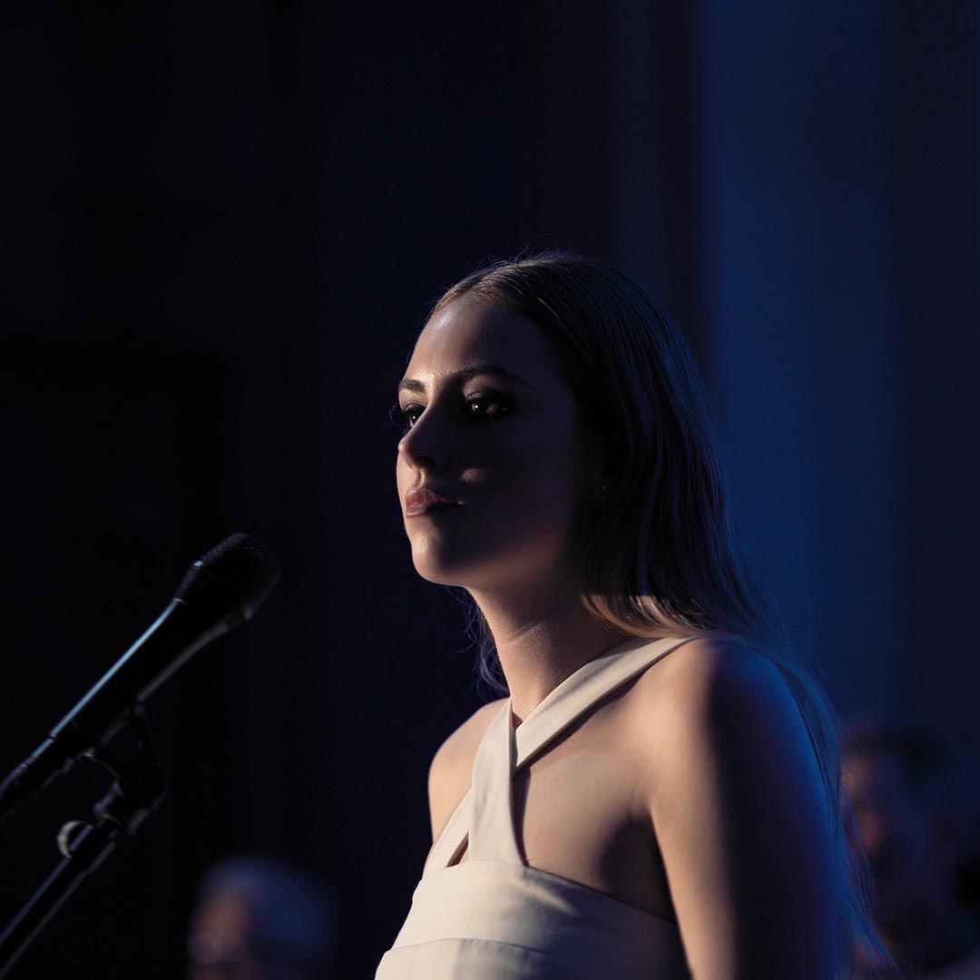 Video still of Campbell performing in the Grand Foyer of Auckland Museum for the exhibition Volume Making Music in Aotearoa.