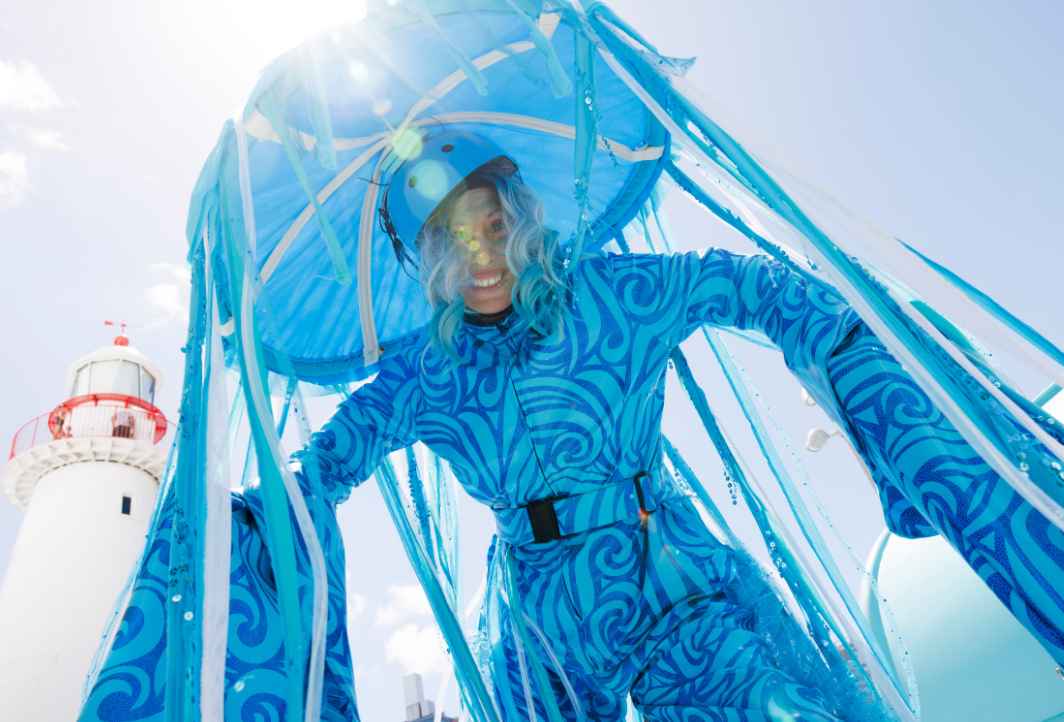 Underwater view of a yellow submarine exploring the hull of a large sunken ship, illuminated by its lights and two smaller submarines nearby.