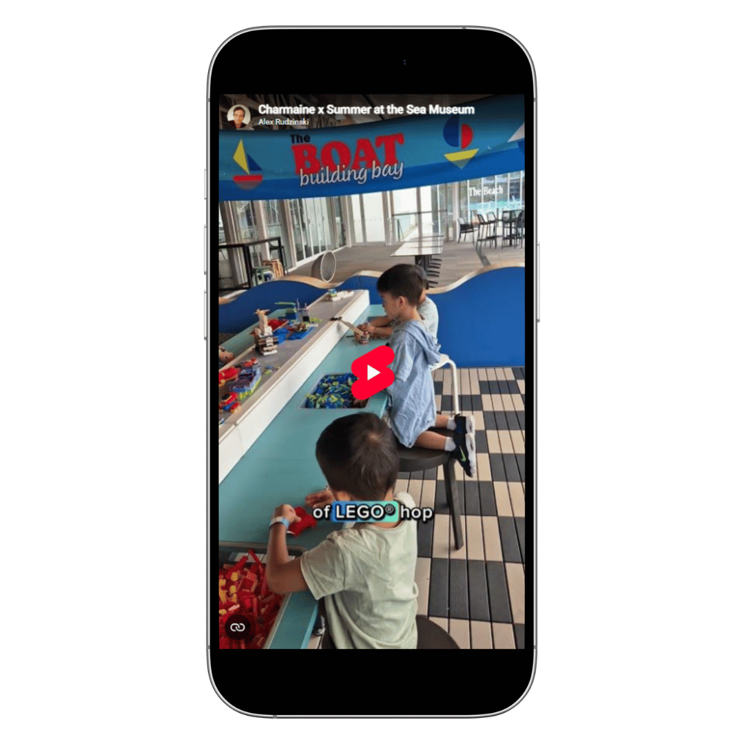 Children playing with LEGO bricks at a boat-building activity table inside a museum space.