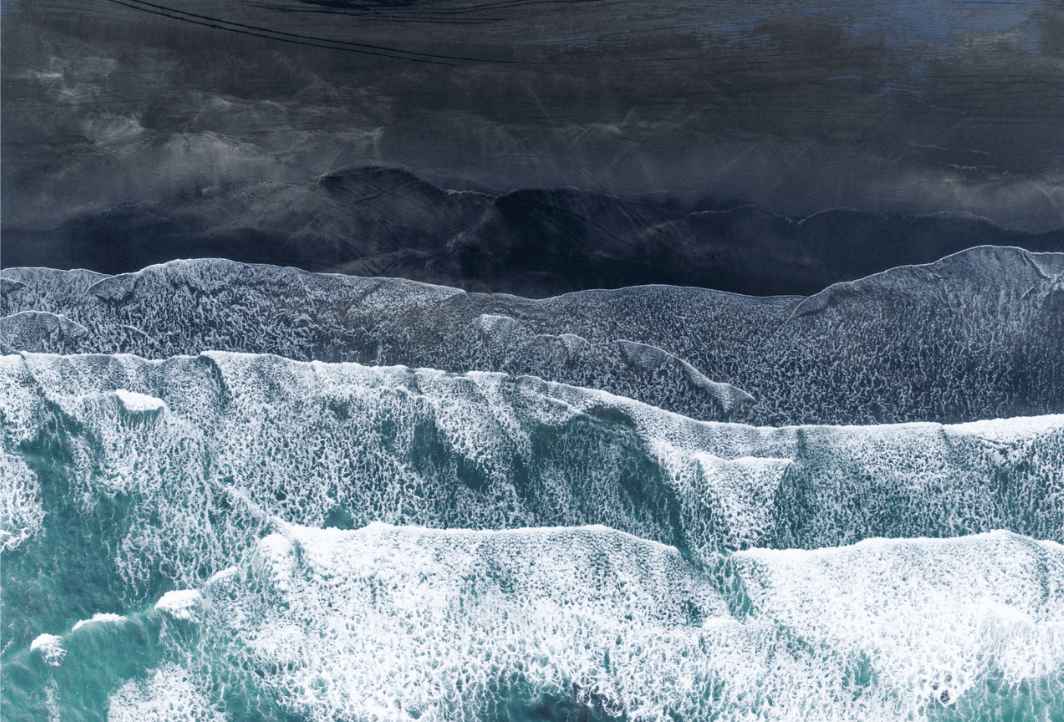 Underwater view of a yellow submarine exploring the hull of a large sunken ship, illuminated by its lights and two smaller submarines nearby.