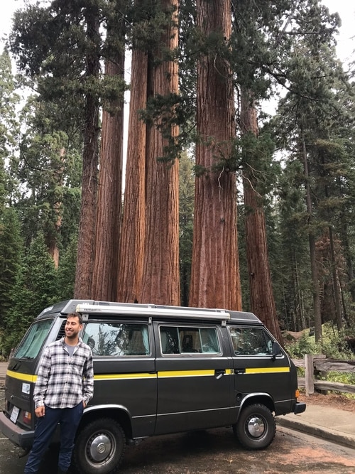 Founder with van and large pine trees in background