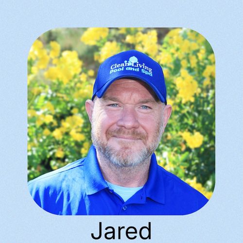 A man in a blue polo shirt poses outdoors by a pool