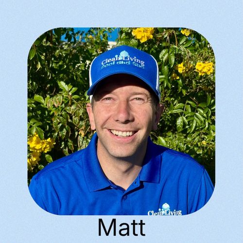 A person wearing a blue cap and shirt poses in front of a calm water