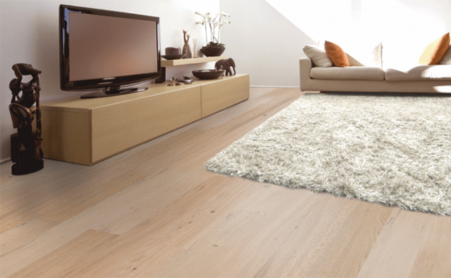 Sand coloured hardwood flooring, with white rug in centre of living area.