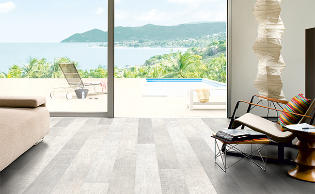Laminate flooring in different shades of grey in living area that leads out to pool deck.