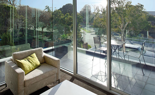 Low iron glass window wall and sliding glass doors in living area with views of the outdoor patio and scenery.