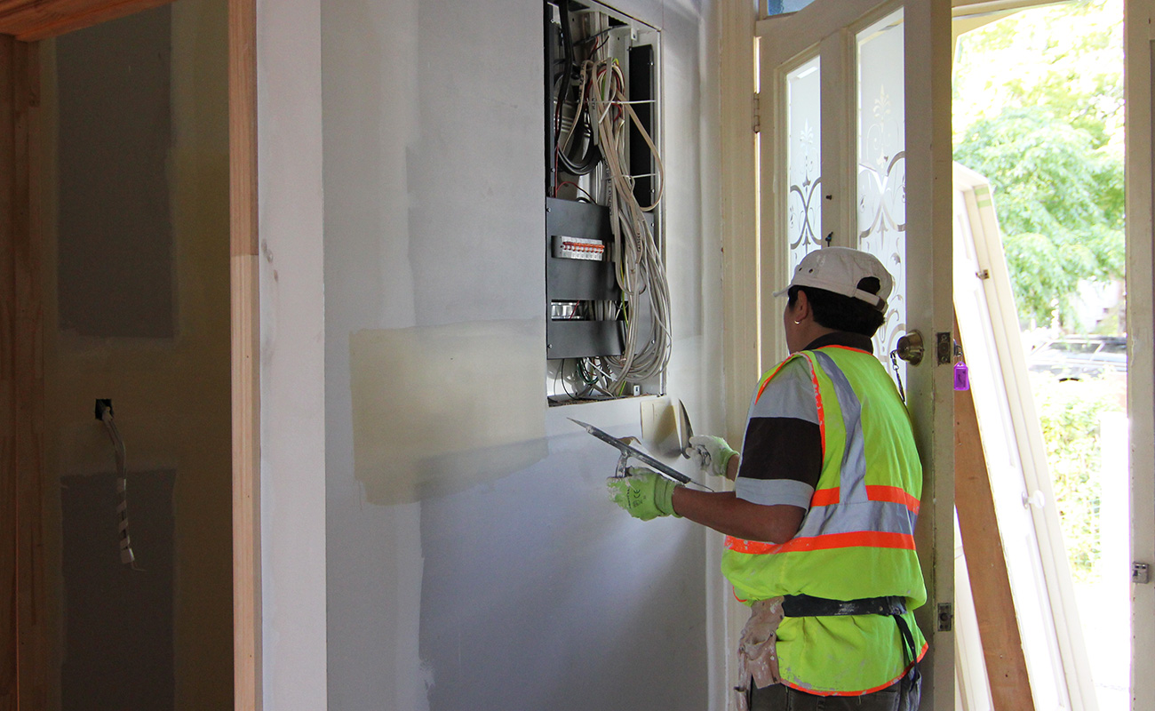 Professional connecting new switchboard in wall behind front entrance door.