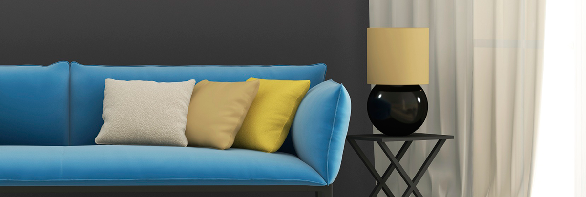 Blue couch with yellow throw pillows against grey wall.