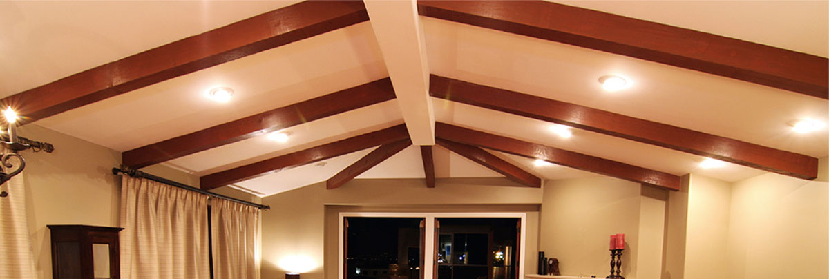 Cathedral ceiling with up-lighting between exposed beams in open-plan living area