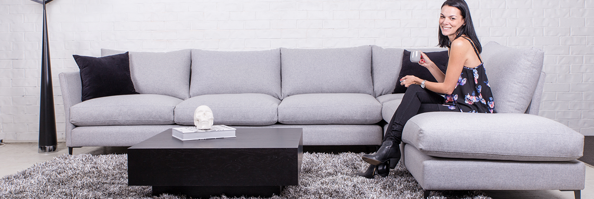 Woman sitting on grey couch in an open plan living space