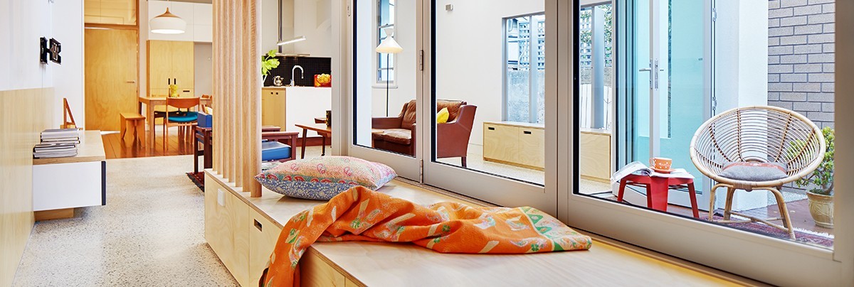Corridor leading to open-plan living area and lined with bi-fold windows overlooking into courtyard