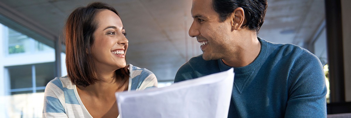 Smiling couple reviewing paperwork concerning tax changes to renovating for investment in New Zealand.\n