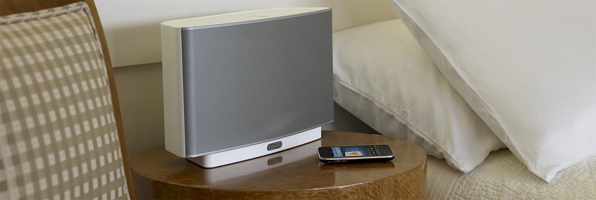 White Sonos wireless speaker and iphone with Sonos Play 5 app.