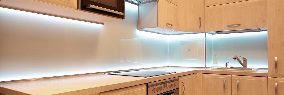 Kitchen cupboards with light blue tinted light bulbs underneath.\n
