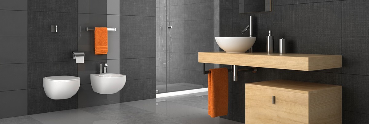 Renovated bathroom with different shades of grey paneling with glass enclosed shower and white vanity and toilet.