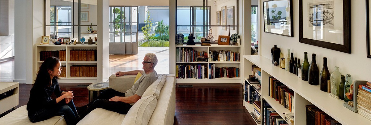 A man and women sitting on couches in renovated Sydney living room.