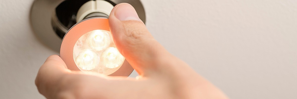Person putting an LED light into a ceiling light fixture.