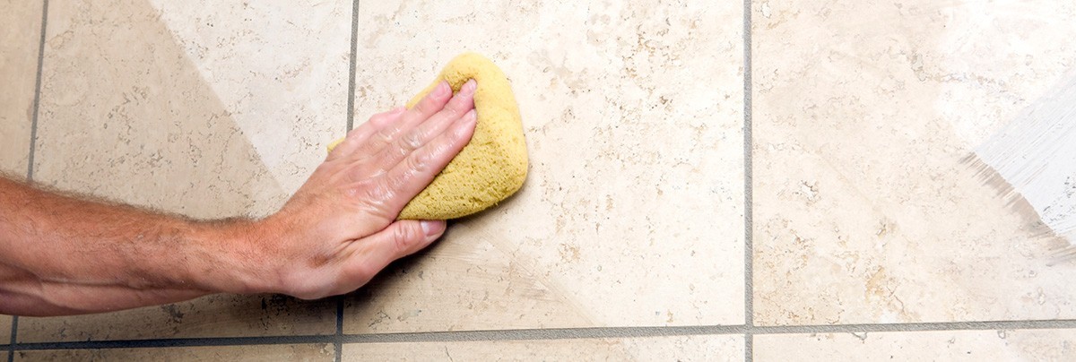 Person cleaning tiles and grout in bathroom