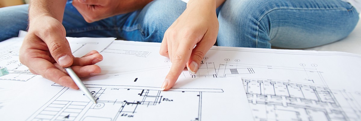 Couple looking at house plans to decide where to create a new bedroom or bathroom.