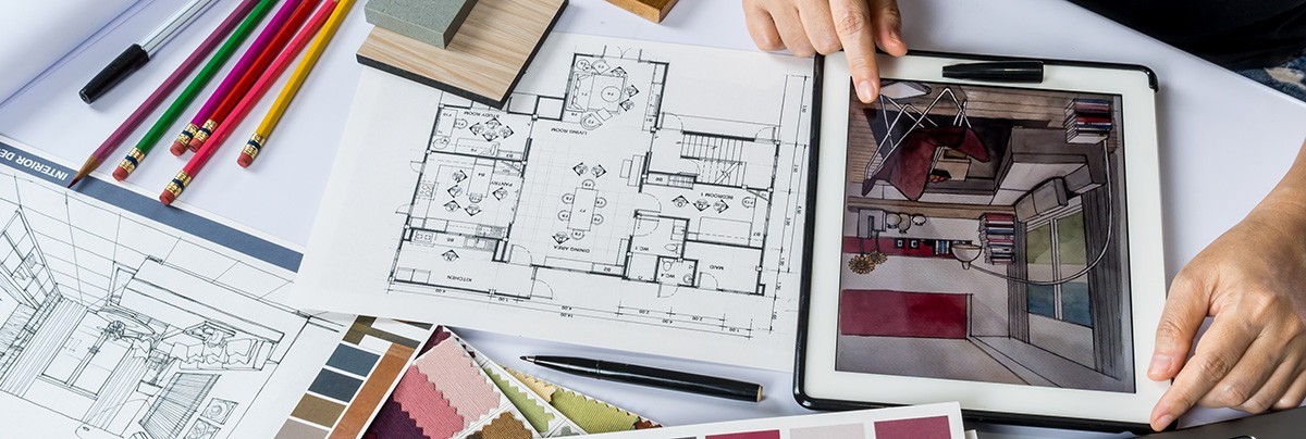 Designer working on colour schemes and architectural plans with the help of a tablet and a computer