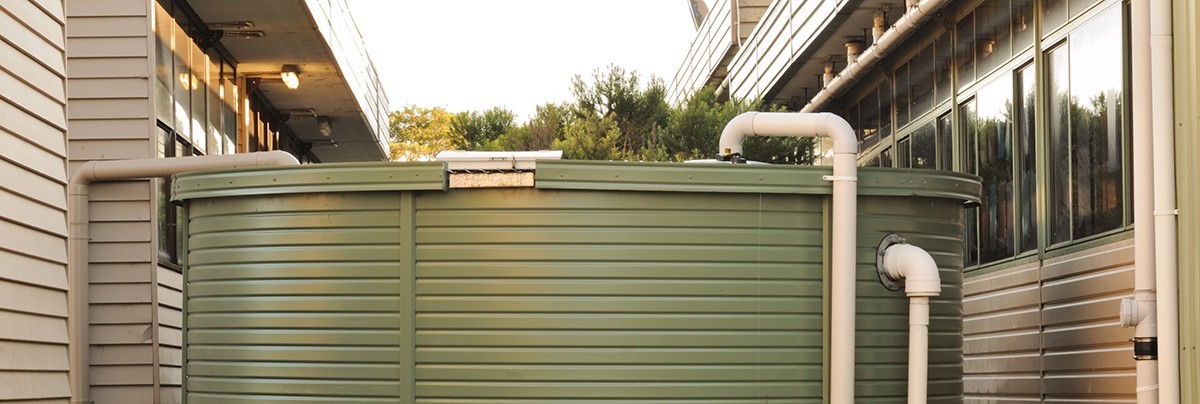 Rainwater tank installed between and connected to two houses
