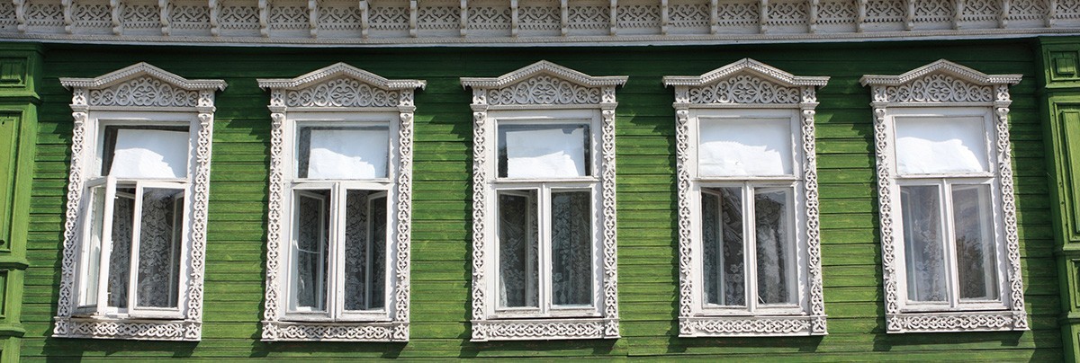 Green house with white framed and pointed windows with mouldings
