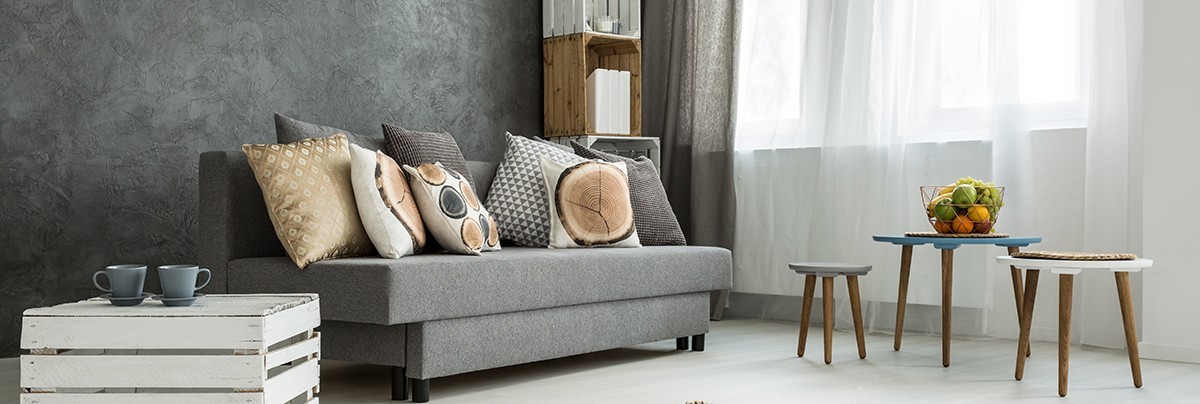 A living room with concrete wall and grey sofa