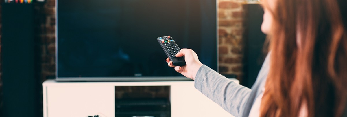 A lady was using a remote to open the TV
