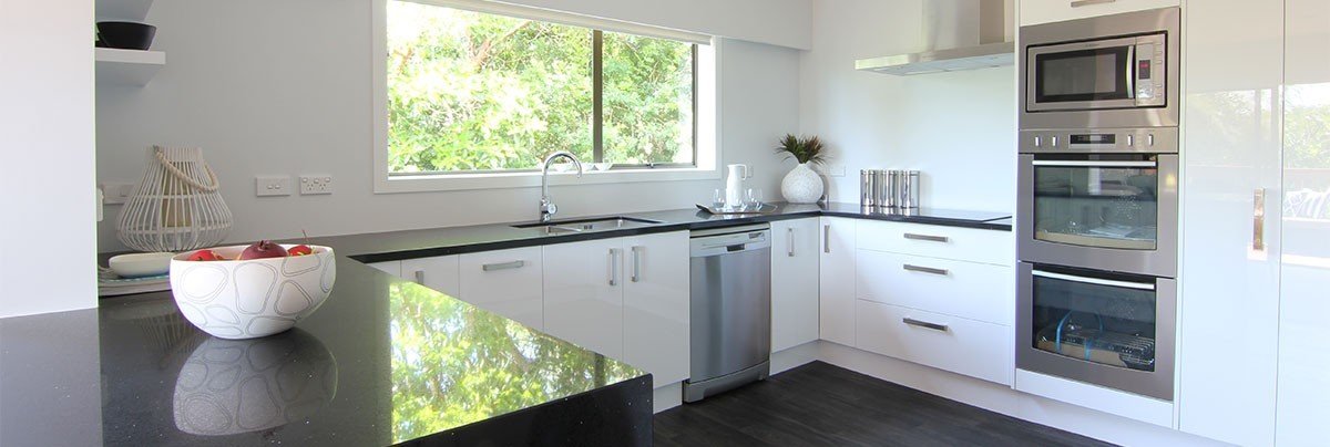 Revamped kitchen with high-gloss white cabinetry and black vinyl flooring