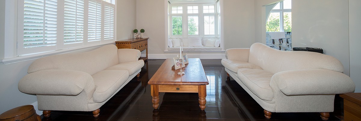 Renovated living room with dark stained floors with white furniture and wooden coffee table