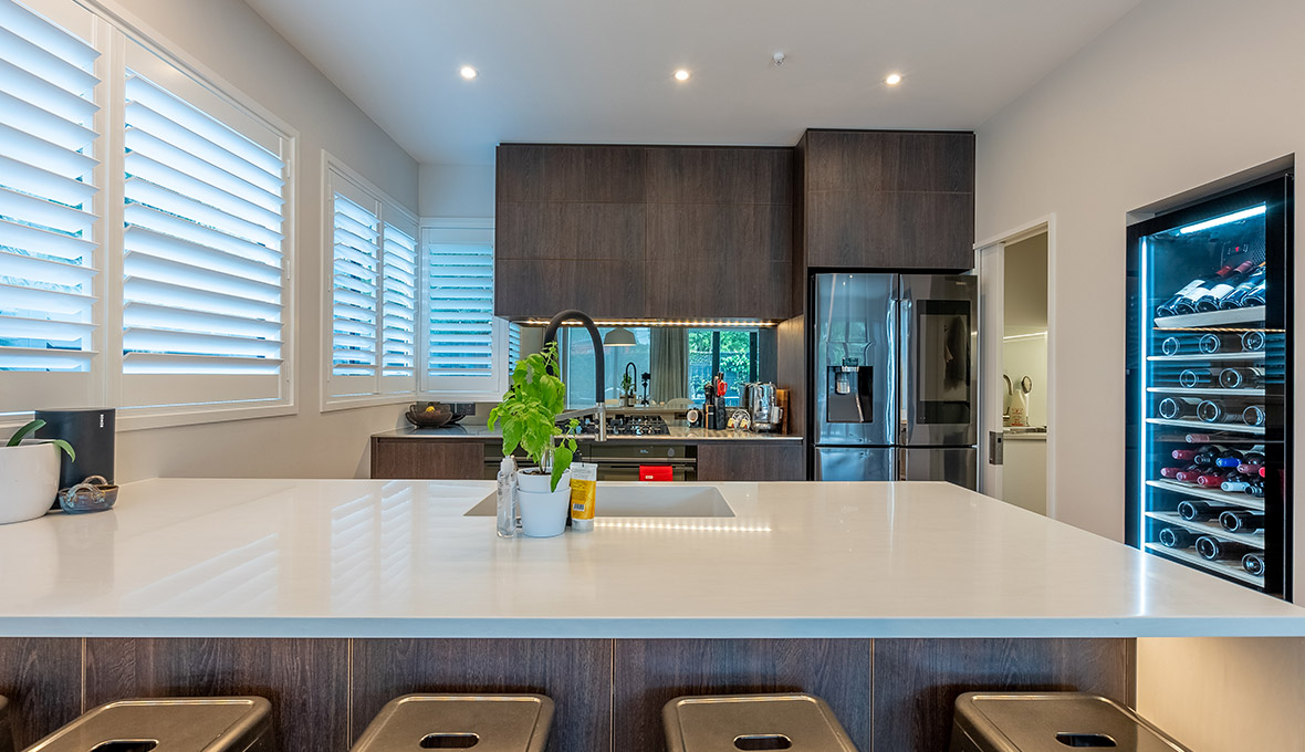 Modern White Kitchen Renovation in Point Chevalier, Auckland with bar fridge storage solution by Dave Georgetti at Refresh Renovations
