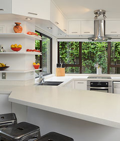 Revamped kitchen with creamy stone flecked Cheltenham bench surface and open-faced corner wall shelves