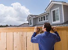 Man looking over pine fence