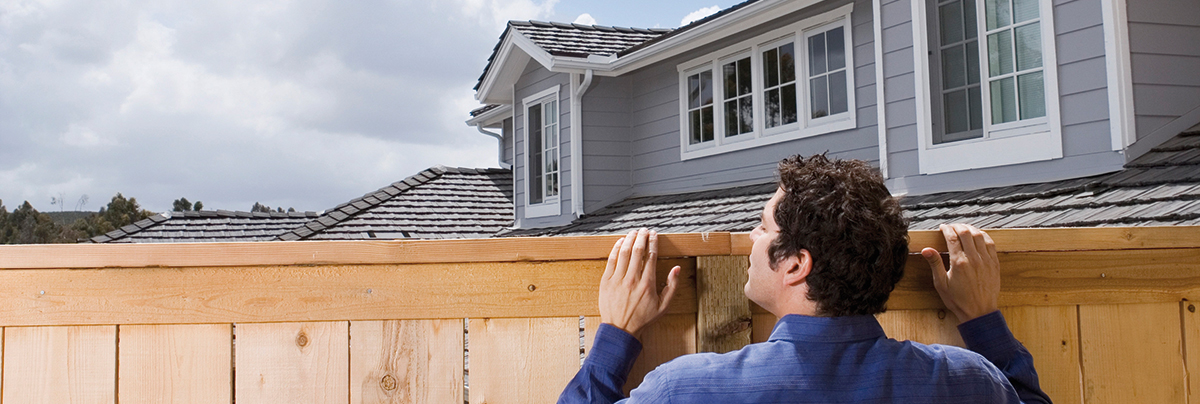 Man looking over pine fence