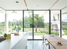 Full length glass wall in open plan kitchen and dinning area, giving view to countryside