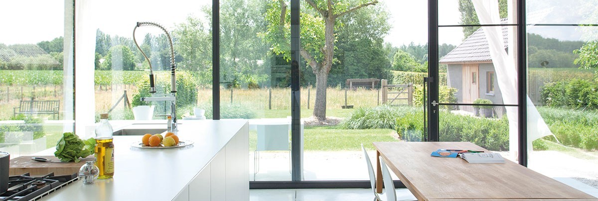 Full length glass wall in open plan kitchen and dinning area, giving view to countryside