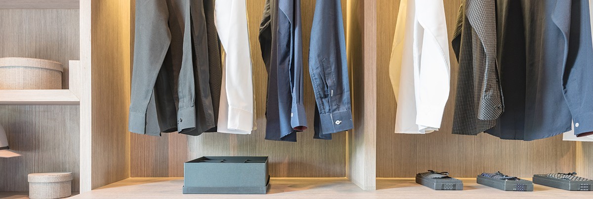 Clothes hanging on a wooden walk-in wardrobe with shelving