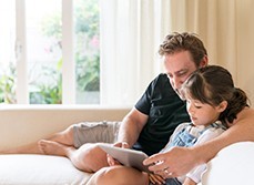 Father and daughter cool down on their living room next to a high window