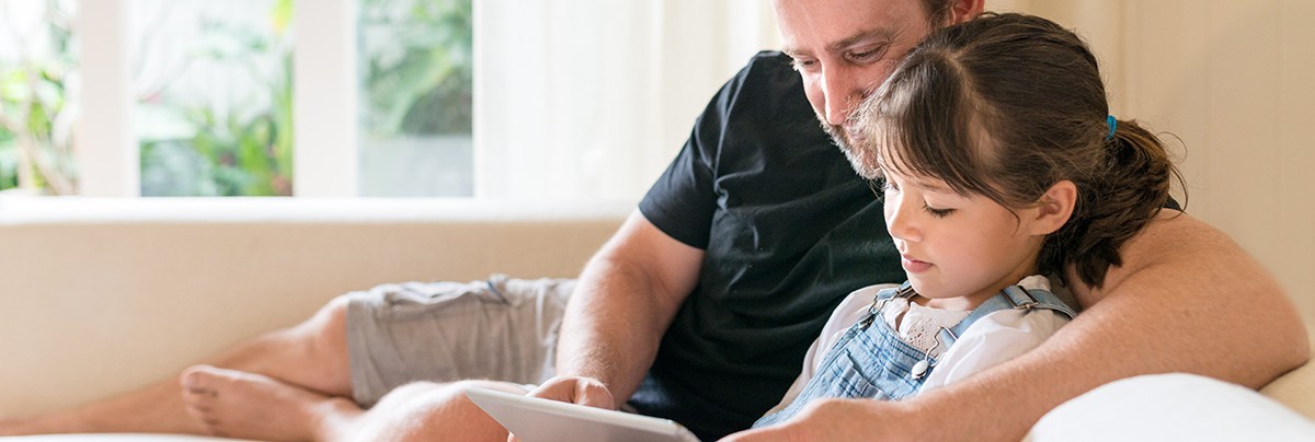 Father and daughter cool down on their living room next to a high window