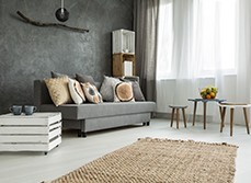 A living room with concrete wall and grey sofa