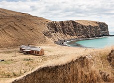 The modern farmhouse sits alone next to the bay