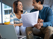 Smiling couple reviewing paperwork concerning tax changes to renovating for investment in New Zealand.\n