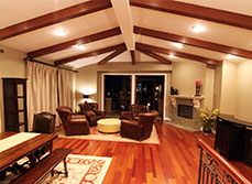 Cathedral ceiling with up-lighting between exposed beams in open-plan living area