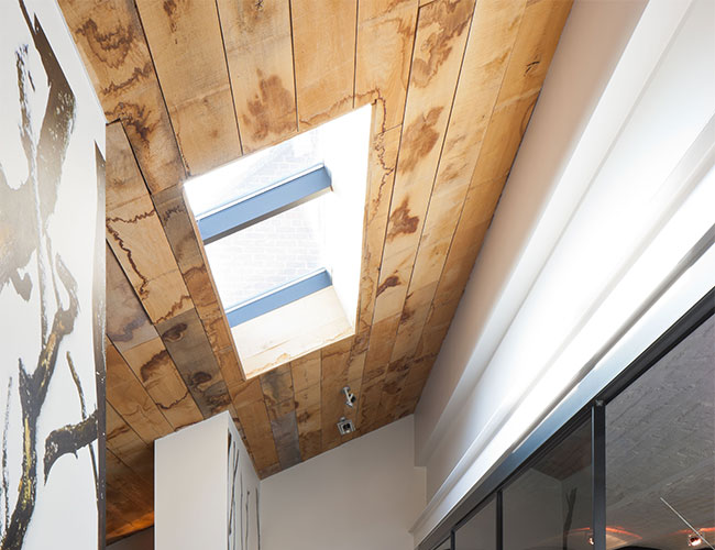 Light coloured wood panelled ceiling with skylights 